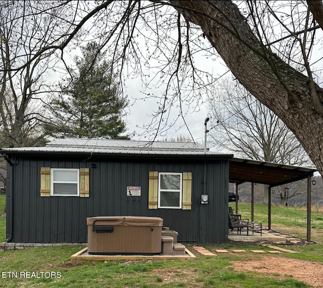 rear view of house featuring a lawn and a hot tub