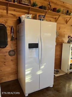 kitchen with white refrigerator with ice dispenser and wooden walls