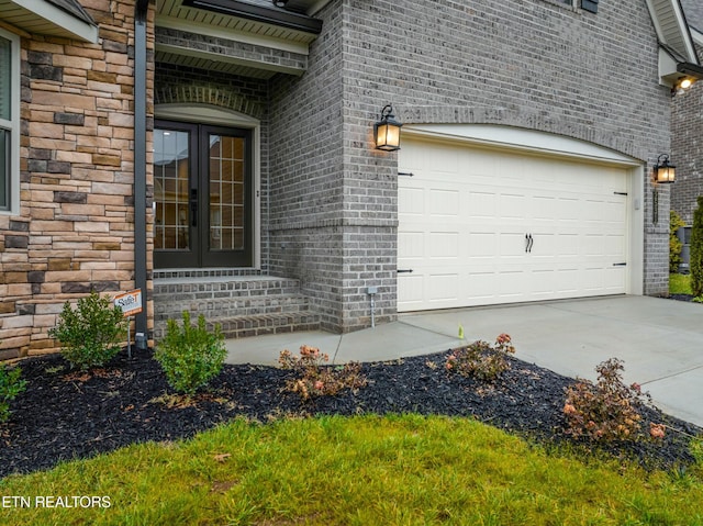 view of exterior entry featuring a garage and french doors