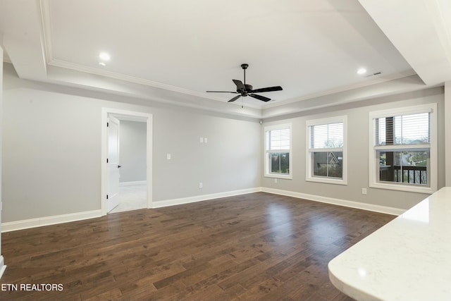 unfurnished living room with a raised ceiling, ceiling fan, dark hardwood / wood-style flooring, and a wealth of natural light