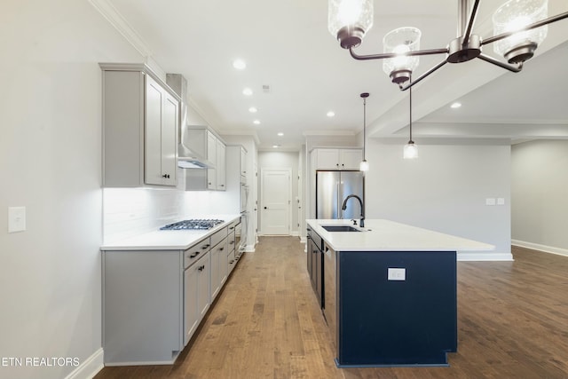 kitchen with stainless steel appliances, a kitchen island with sink, a chandelier, hardwood / wood-style floors, and hanging light fixtures