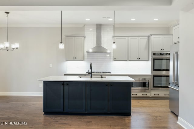 kitchen with hardwood / wood-style floors, white cabinets, wall chimney range hood, and hanging light fixtures