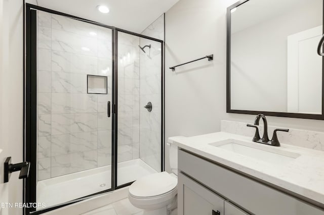 bathroom featuring tile patterned floors, vanity, a shower with shower door, and toilet