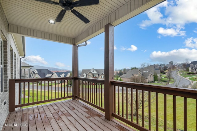 wooden terrace with a lawn and ceiling fan