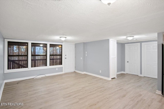 spare room with a textured ceiling and light wood-type flooring