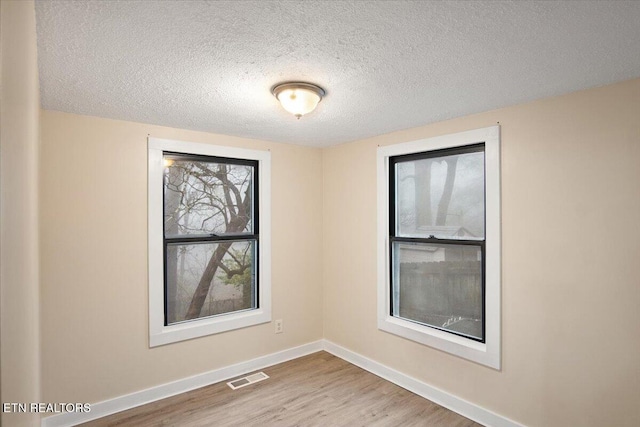 unfurnished room with light hardwood / wood-style floors and a textured ceiling