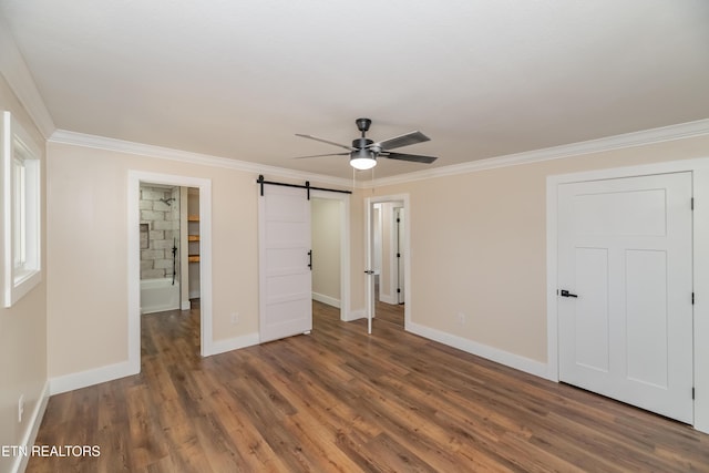 unfurnished bedroom featuring ceiling fan, a barn door, dark hardwood / wood-style flooring, and crown molding