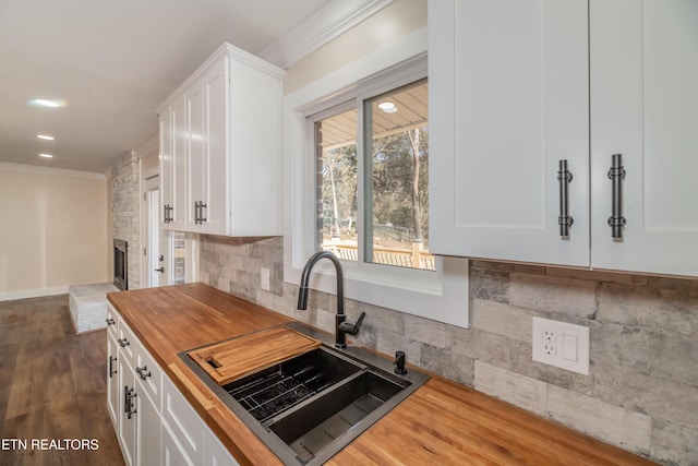 kitchen with butcher block counters, sink, and white cabinets