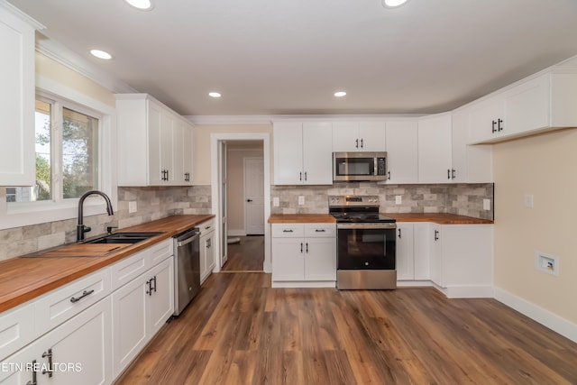 kitchen with wood counters, appliances with stainless steel finishes, backsplash, white cabinets, and dark hardwood / wood-style floors