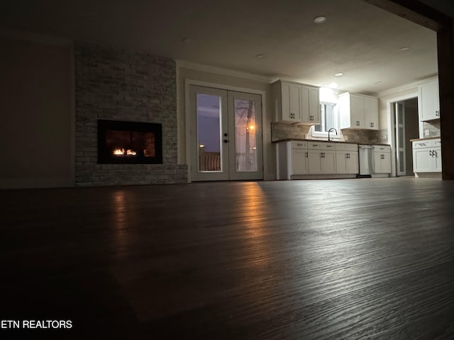 unfurnished living room with dark wood-type flooring, french doors, sink, a brick fireplace, and ornamental molding