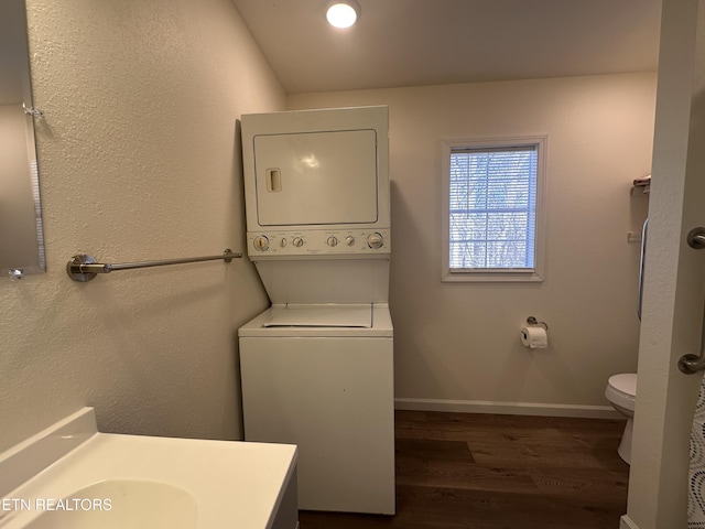 washroom with dark hardwood / wood-style floors and stacked washer / drying machine