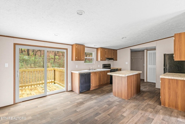 kitchen featuring dark wood-type flooring, crown molding, a textured ceiling, a kitchen island, and black appliances