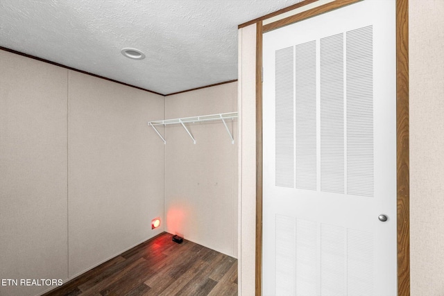 laundry area featuring a textured ceiling, dark hardwood / wood-style floors, and ornamental molding