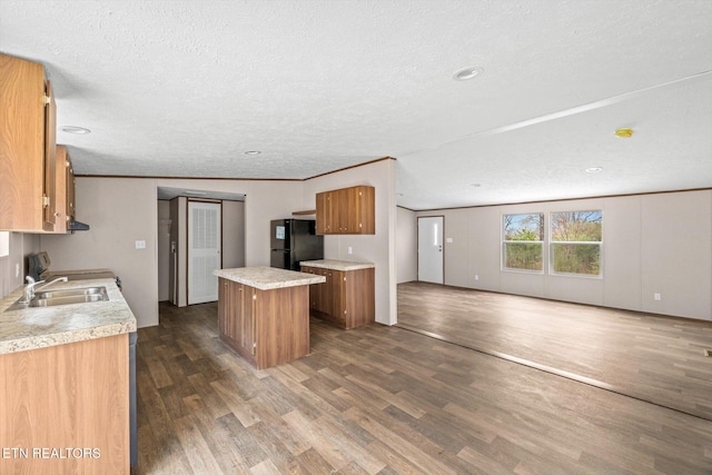 kitchen with a center island, sink, black fridge, dark hardwood / wood-style floors, and a textured ceiling