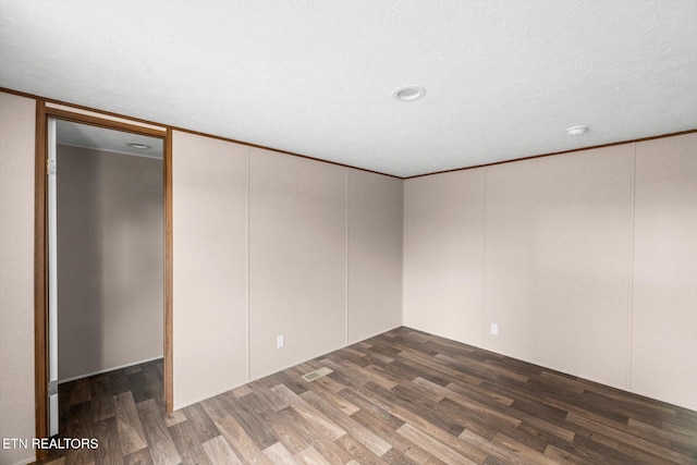 empty room with a textured ceiling and dark hardwood / wood-style floors