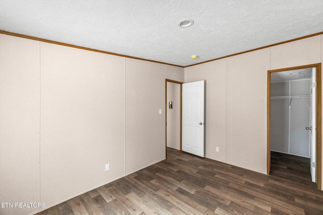 unfurnished bedroom with a textured ceiling, dark hardwood / wood-style floors, and ornamental molding