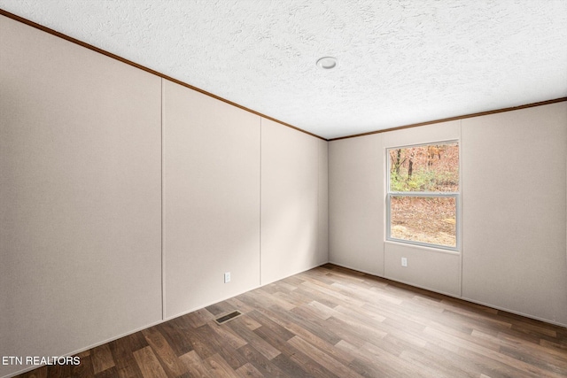 unfurnished room featuring crown molding, light hardwood / wood-style floors, and a textured ceiling