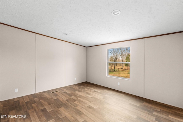 unfurnished room with a textured ceiling, light hardwood / wood-style floors, and crown molding