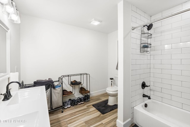 full bathroom with vanity, toilet, tiled shower / bath, and hardwood / wood-style flooring