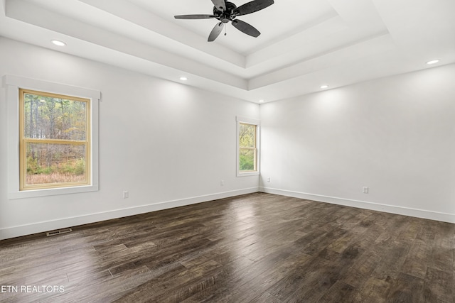 spare room with dark wood-type flooring, a tray ceiling, and baseboards