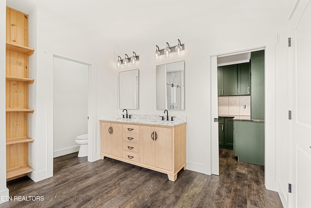 bathroom with toilet, double vanity, a sink, and wood finished floors