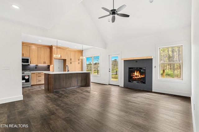 kitchen featuring light countertops, a center island with sink, dark wood-style floors, open floor plan, and stainless steel appliances