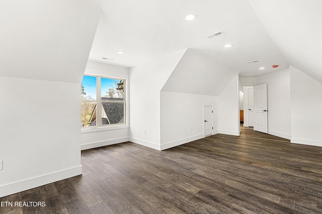 bonus room with dark wood-type flooring, baseboards, visible vents, and vaulted ceiling