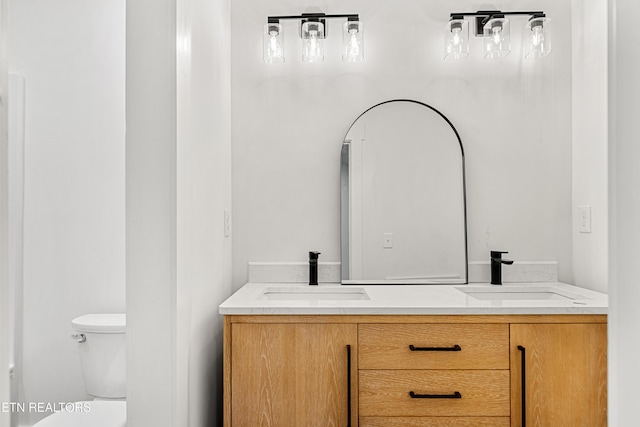 full bath featuring double vanity, a sink, and toilet