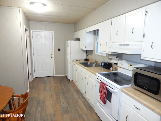 kitchen with wood walls, white appliances, dark wood-type flooring, white cabinets, and sink