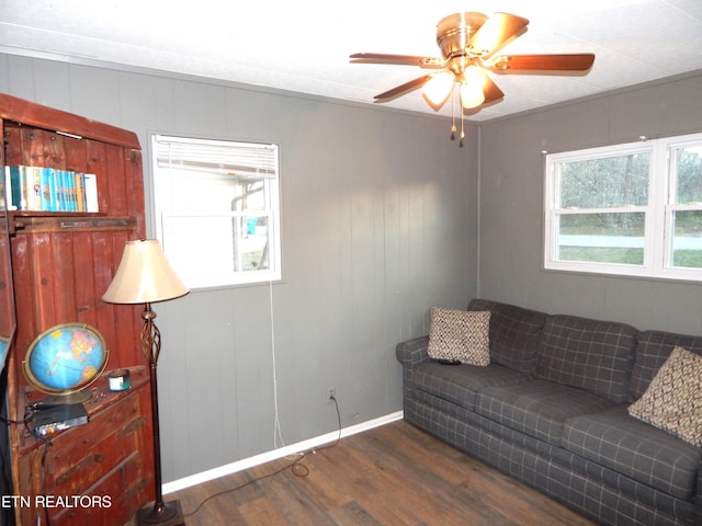 living room with dark hardwood / wood-style flooring, ceiling fan, and wood walls