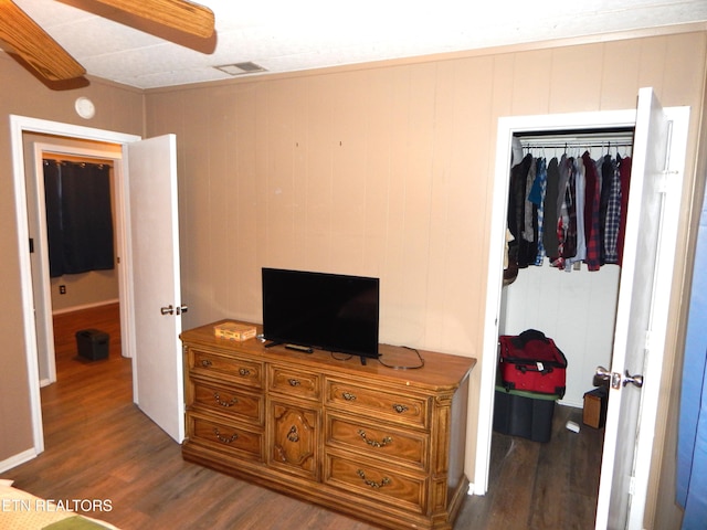 bedroom featuring wooden walls, a closet, and dark wood-type flooring