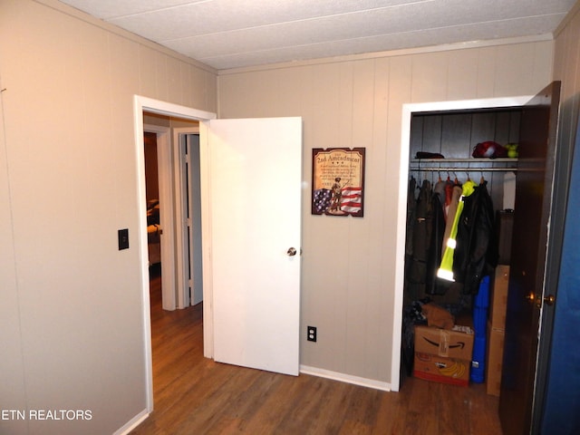 bedroom featuring wood walls, dark wood-type flooring, and a closet