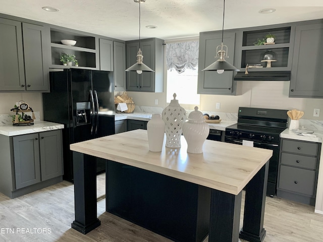 kitchen featuring black appliances, decorative light fixtures, and light wood-type flooring