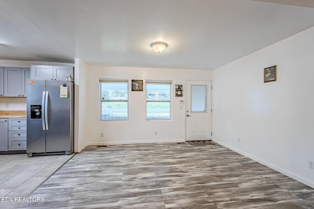 kitchen with stainless steel fridge with ice dispenser, light wood-type flooring, and gray cabinetry