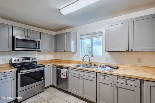 kitchen featuring wooden counters, gray cabinetry, stainless steel appliances, sink, and light tile patterned floors