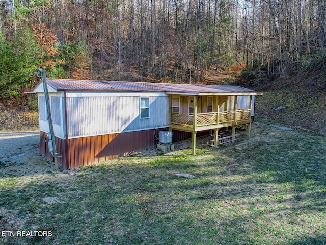 view of front facade featuring a wooden deck, a front yard, and central AC