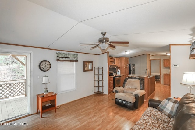 living room with ceiling fan, sink, light wood-type flooring, vaulted ceiling, and ornamental molding