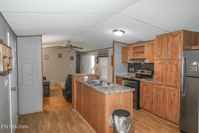 kitchen with a center island with sink, sink, light wood-type flooring, appliances with stainless steel finishes, and tasteful backsplash