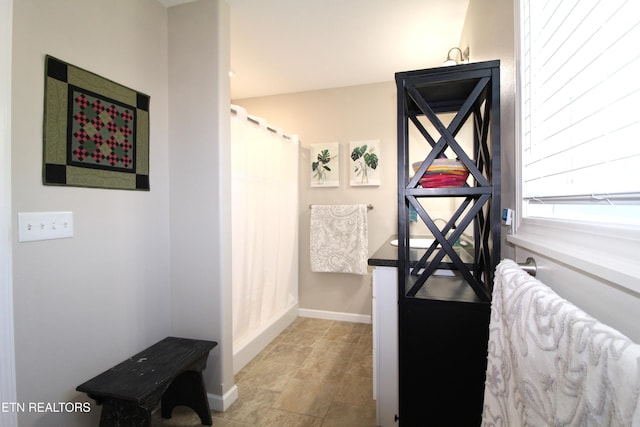 full bath featuring curtained shower and baseboards