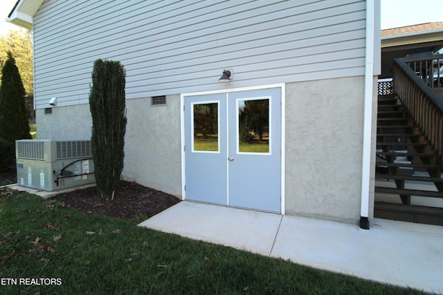 rear view of house with crawl space, stairs, central AC unit, and stucco siding