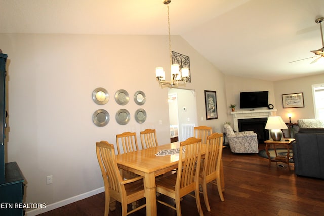 dining space featuring dark wood-style floors, a fireplace, vaulted ceiling, and ceiling fan with notable chandelier