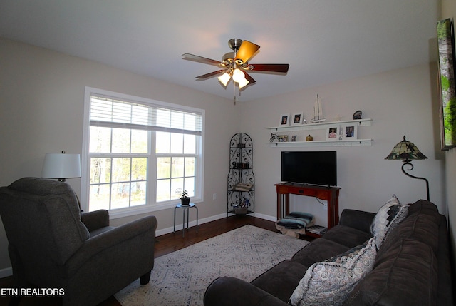 living area featuring a ceiling fan, baseboards, and wood finished floors