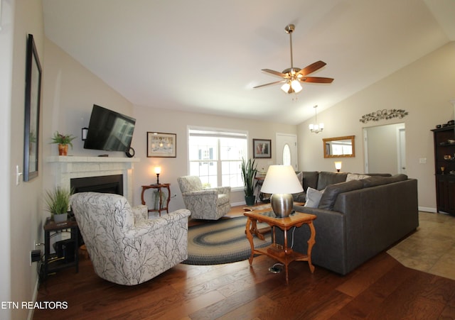 living area with a fireplace, vaulted ceiling, dark wood-type flooring, and ceiling fan with notable chandelier