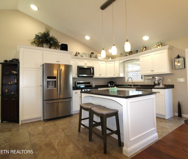 kitchen with dark countertops, a kitchen island, white cabinetry, and stainless steel appliances