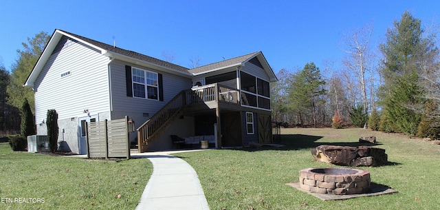 view of front of home with stairway, a fire pit, a sunroom, and a front yard