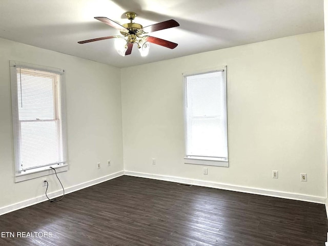 spare room featuring ceiling fan, dark hardwood / wood-style flooring, and a healthy amount of sunlight