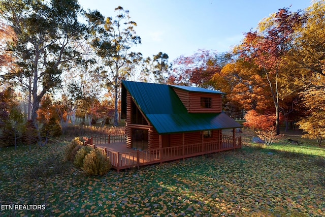 exterior space with log exterior, a lawn, and metal roof