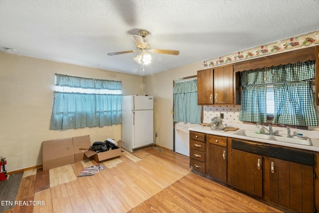 kitchen featuring light hardwood / wood-style floors, white refrigerator, a healthy amount of sunlight, and a textured ceiling