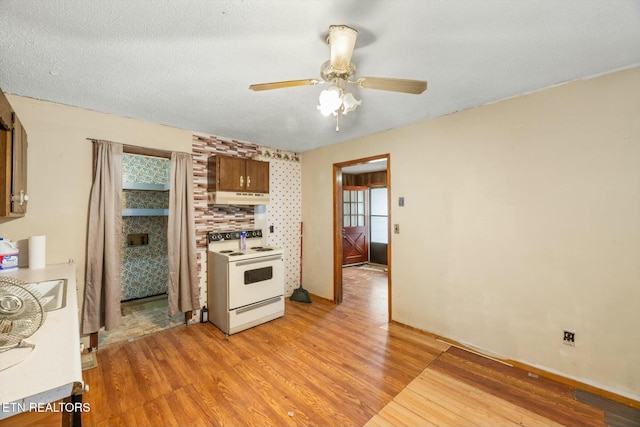 kitchen featuring electric range, light hardwood / wood-style flooring, ceiling fan, and a textured ceiling