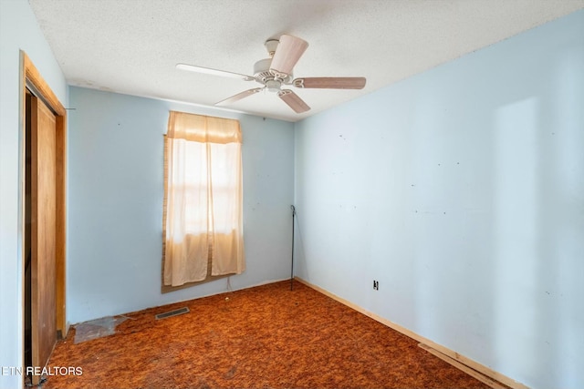 carpeted empty room with ceiling fan and a textured ceiling